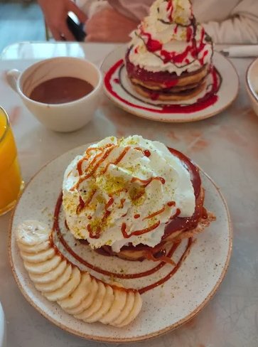 Montagne de pancakes nappée de chantilly, banane et pistache